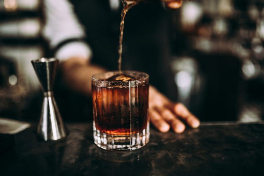 bartender pouring straight bourbon in a glass