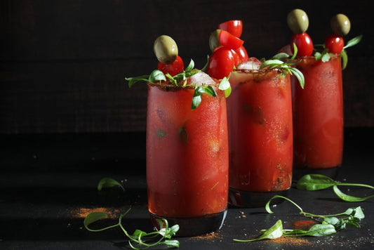 three glasses of bloody mary cocktails on black table with black background