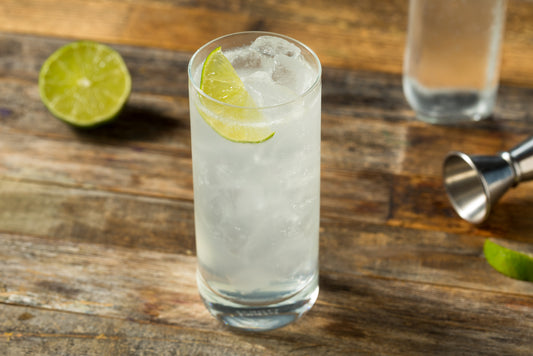 ranch water cocktail with lime on wooden table with bar tools