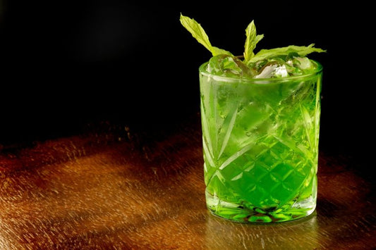 green cocktail in glass with garnish on wooden table