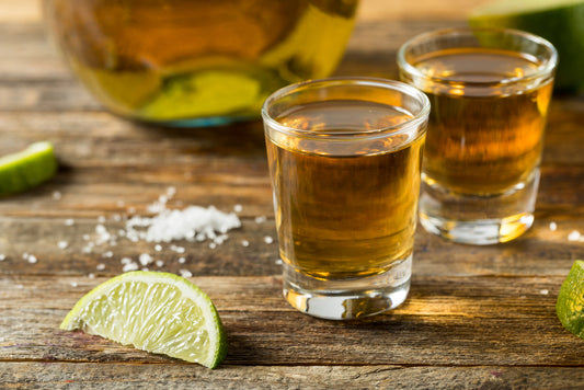 two shots of reposado tequila with salt and sliced limes on table