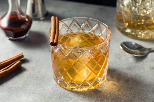cinnamon whiskey garnished with cinnamon stick and with garnishes and bar tools