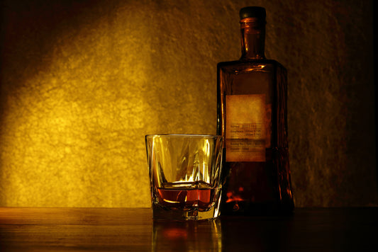 whiskey in glass by bottle with amber lighting