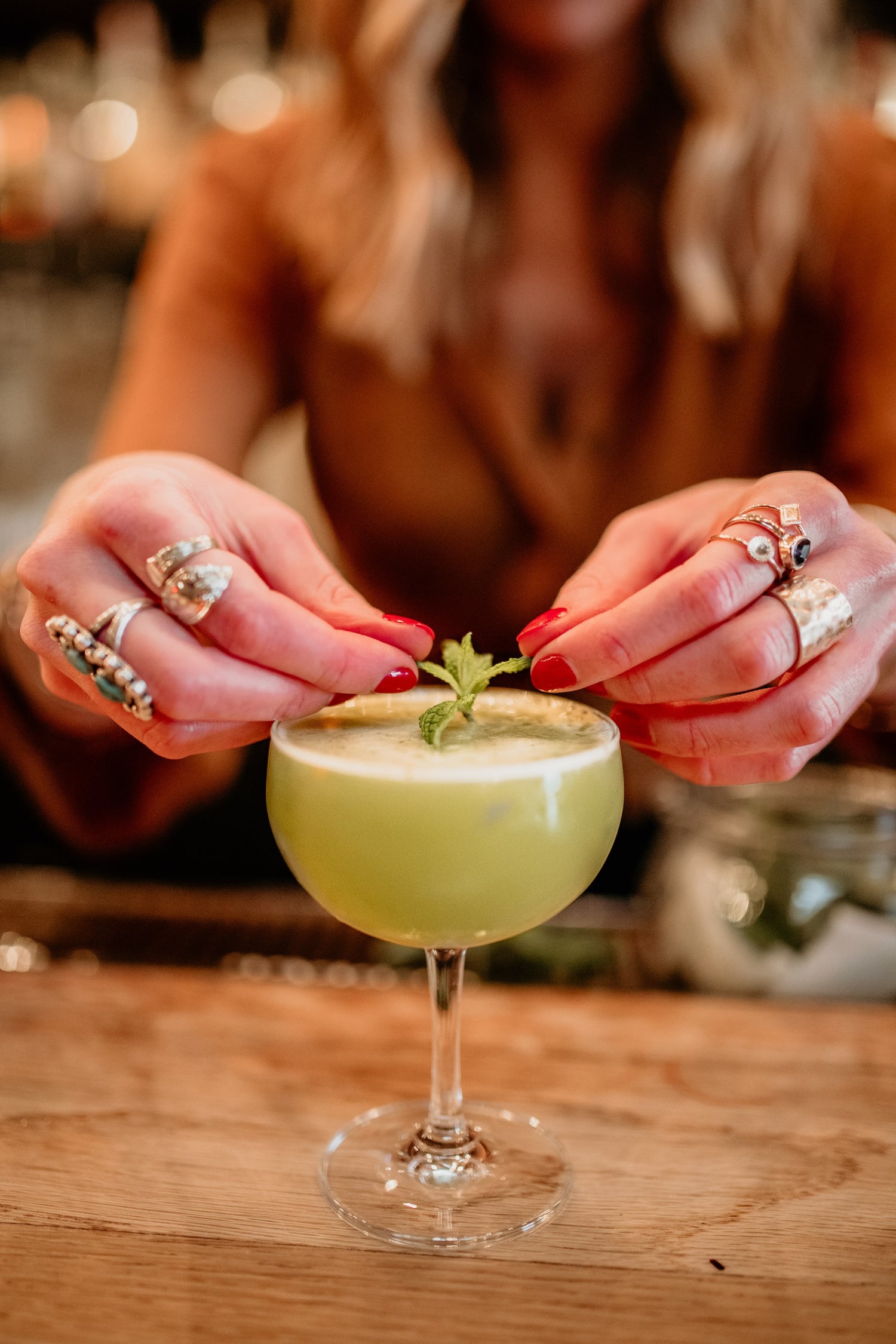 woman garnishing a green cocktail
