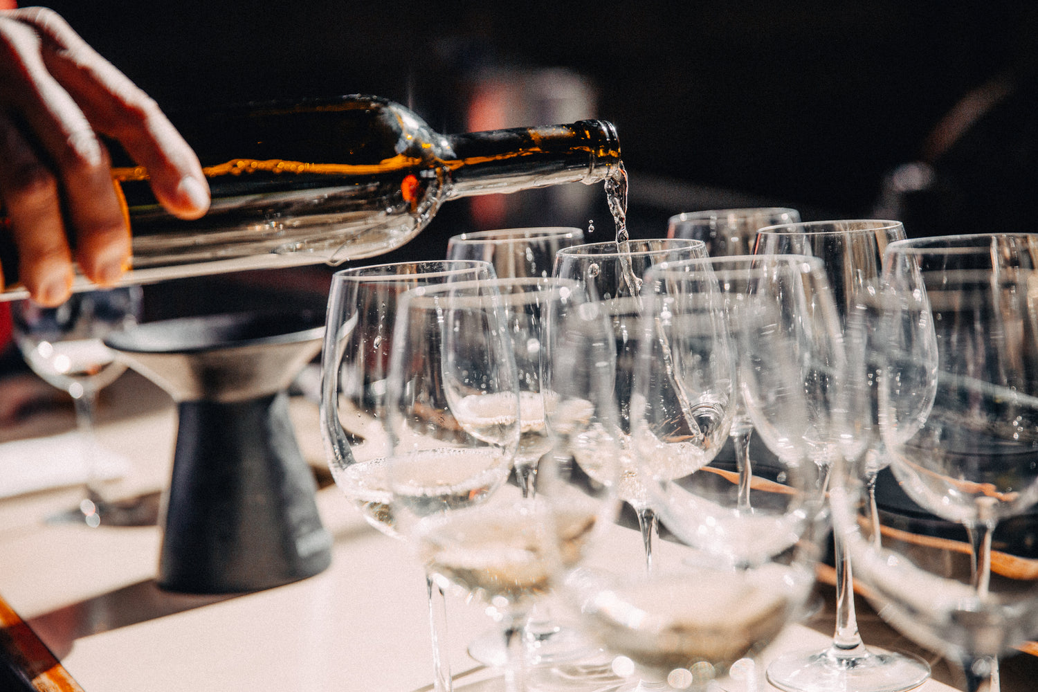 hand pouring bottle of wine into wine glasses