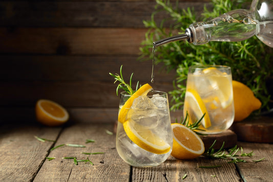 glasses of renais gin with lemon and rosemary garnishes on wooden table