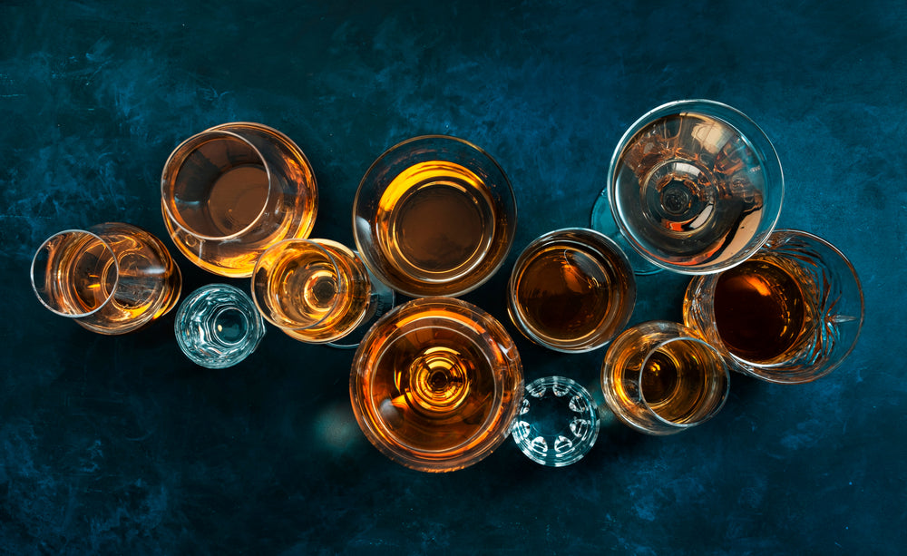 rum and vodka in different glasses viewed from above on dark table