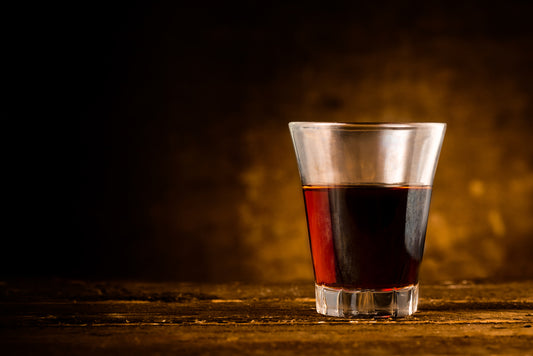 amaro in a glass with spotlight and brown background