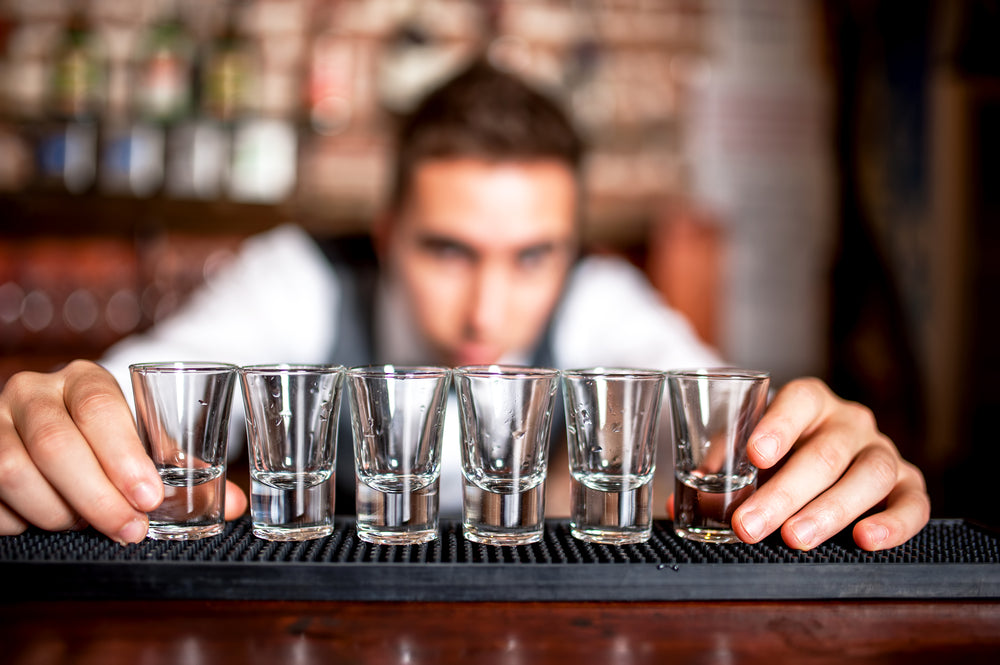 bartender preparing shot glasses in line on bar
