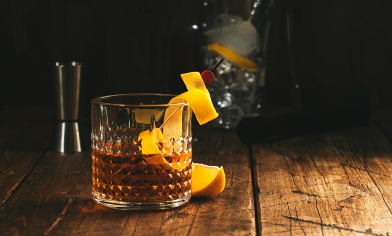 easy bourbon cocktail with orange peel on wooden table with bar tools