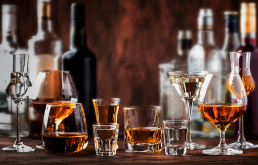 two bitch bourbon poured in various glasses on bar