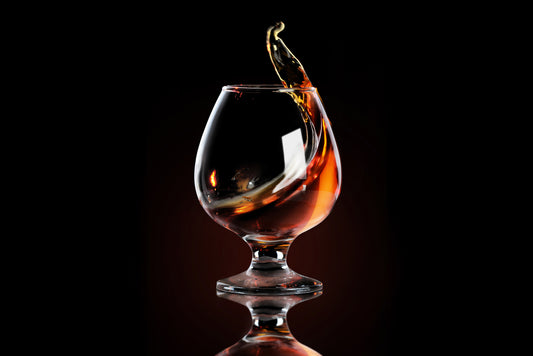 cognac splashing into a glass with black background