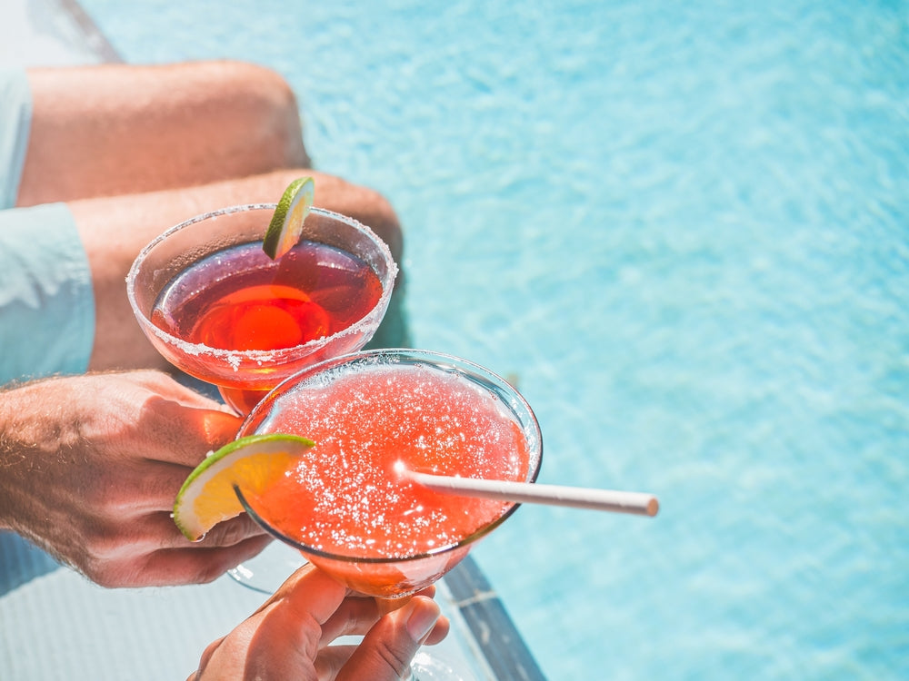couple toasting frozen red cocktails by pool