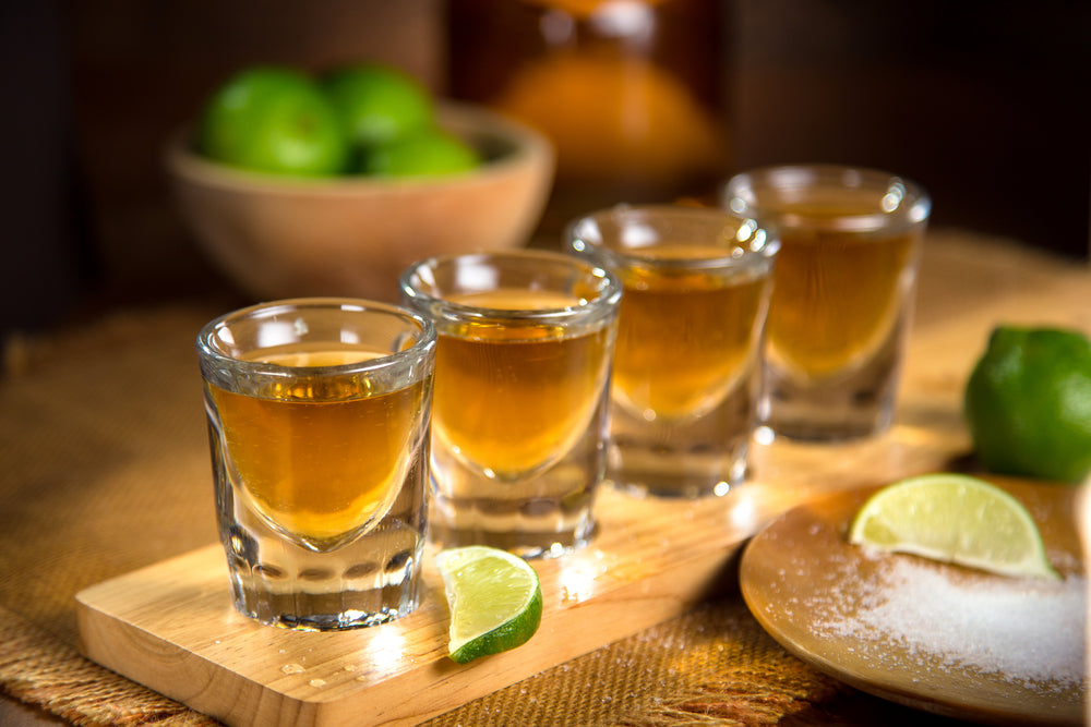 flight of tequila shots with lime and salt on bar with garnishes