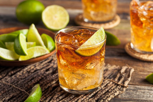 glass of rum cocktail with lime on wooden table