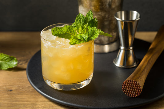 glass of summer whiskey cocktail with mint and barkeeping tools