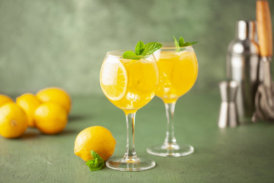 limoncello spritz drinks in cocktail glasses with lemons and barkeeping tools
