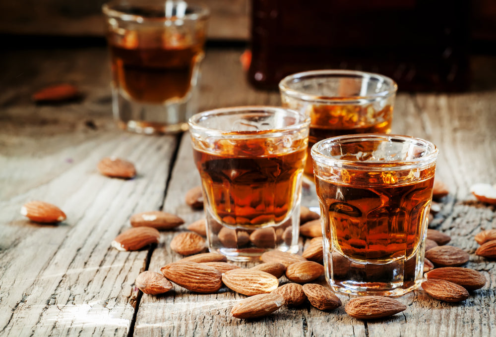 shots of amaretto with smoked almonds on wooden bar