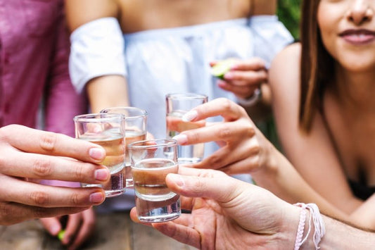four women toasting sipping tequila outside