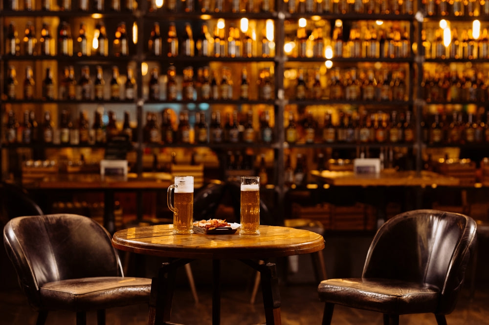  interior of a san antonio speakeasy with leather chairs, two pints, and a wall of liquor bottles