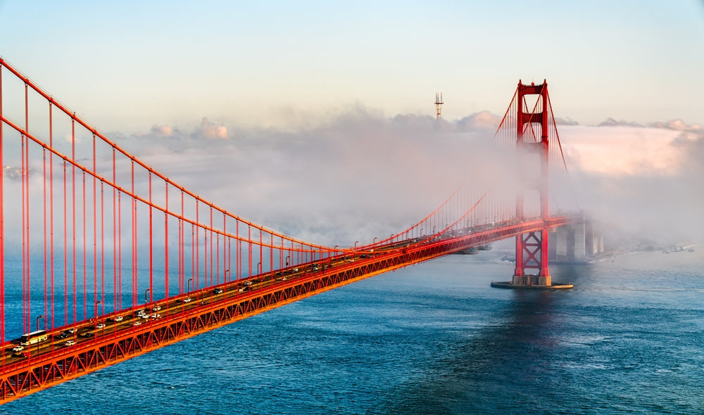 golden gate bridge in san francisco with fog rolling in and a blue sky