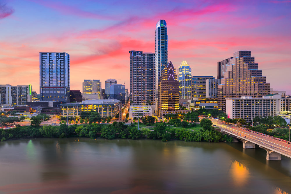 austin texas skyline at sunset with a bridge and the colorado review in view