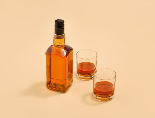 two glasses and bottle containing irish whiskey and scotch