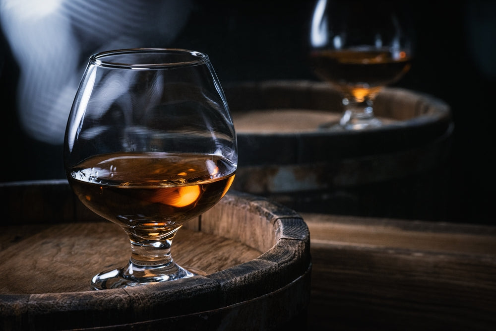 two glasses of brandy on barrels